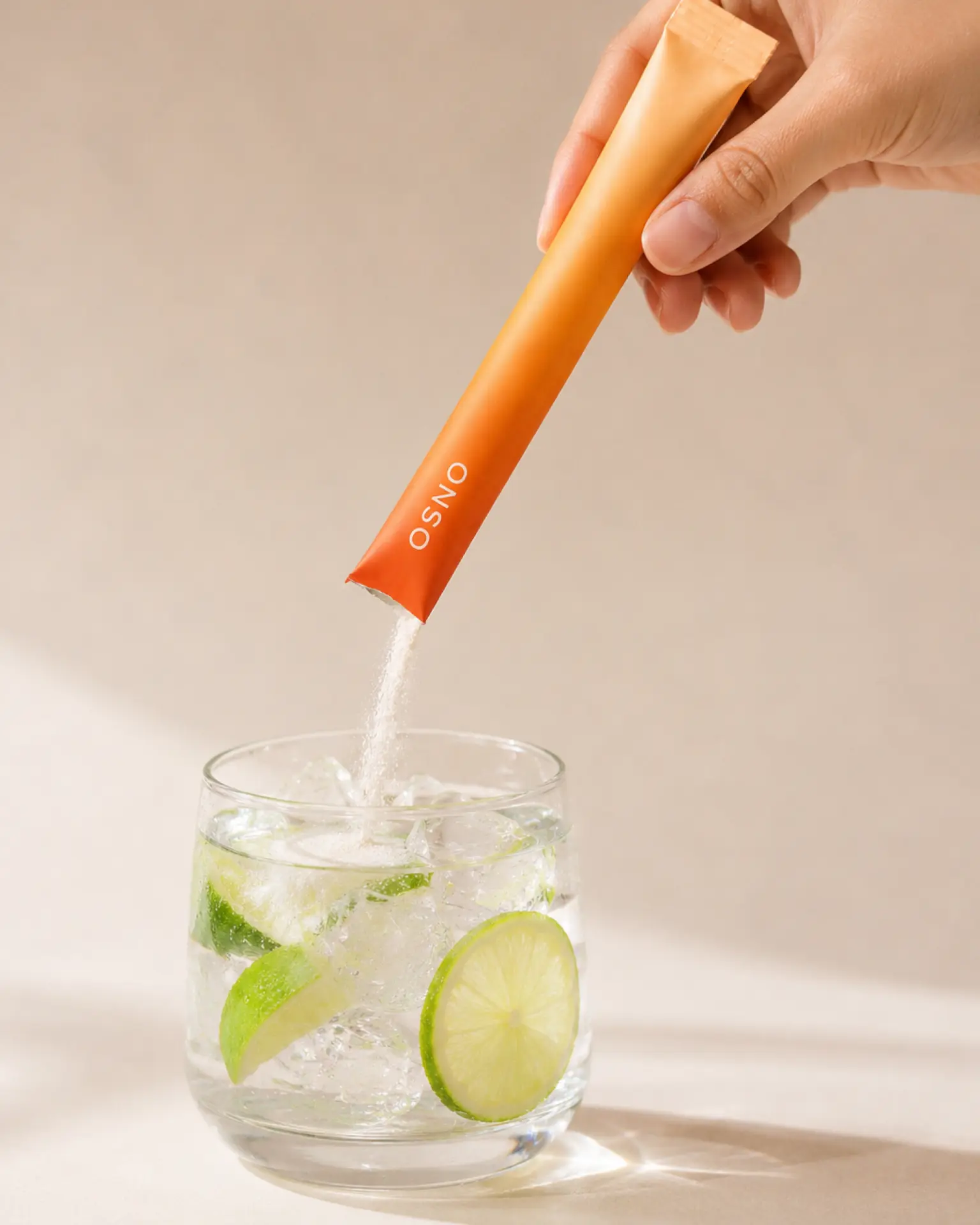 An ONSO stick pouring into a glass of iced water with lime